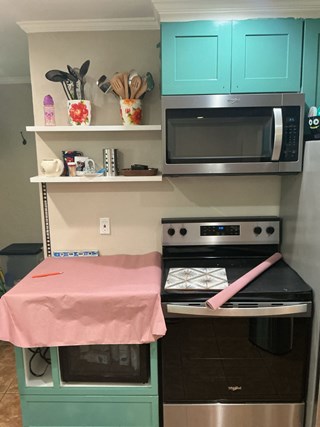Bare kitchen wall before backsplash installation, showing measurement template paper and selected patterned tile sample on the stove, at a Raleigh, NC home by Ace Handyman Services