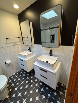 Chapel Hill, NC bathroom remodel with a black accent wall, floating vanities with black hardware, and a stylish geometric tile floor.