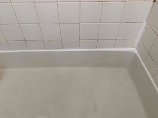 Bathtub area with the caulk newly applied. The area is now clean and sealed, with no visible gaps between the tub and tiles.