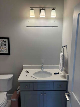 Bathroom with a light fixture installed above the sink, but the area above the countertop is missing a mirror. 