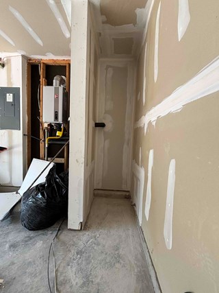 Narrow space after the drywall work is completed. The walls have been patched and finished with joint compound, showing smooth and uniform surfaces.
