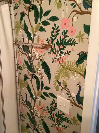 Wall with the floral wallpaper, but now featuring a towel bar installed. 