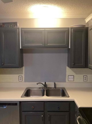 Kitchen after the window has been removed. The space around the sink is now covered with a smooth wall that has been painted.