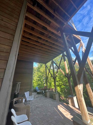 The first image shows a covered outdoor patio beneath a wooden deck with exposed beams and diagonal support posts. 