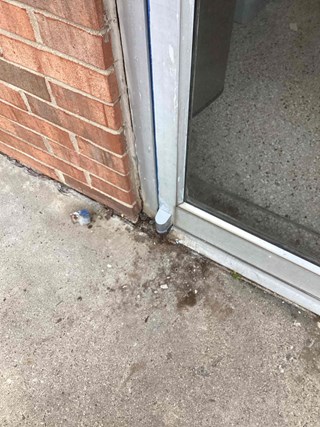 Same door after hinge replacement and maintenance. The rusted hinge has been replaced with a new, clean metal hinge, and the area around the door appears cleaner