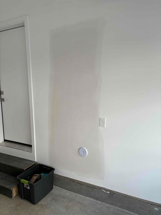  Wall after the drywall has been repaired. The hole has been patched, and the new drywall has been blended with joint compound, creating a smooth surface.
