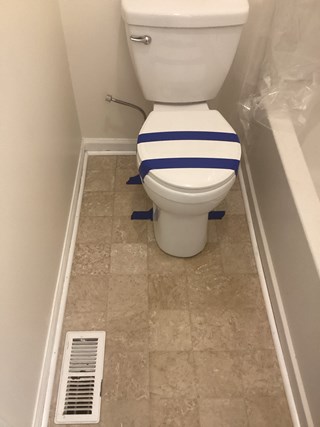 Small bathroom with an old beige vinyl floor that has a dated, marbled pattern. 