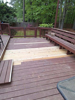 Deck after repair, with new light-colored wooden boards installed to replace the damaged sections. The repair has improved both the structure and aesthetics of the deck.