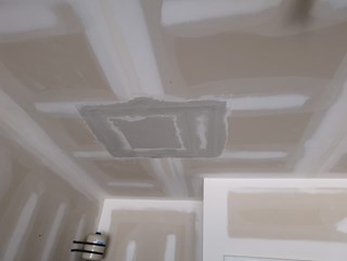 Ceiling after repair, with the hole fully patched and covered with drywall.