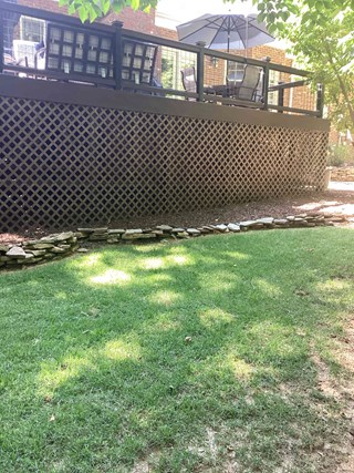 Deck after the installation of lattice panels enclosing the understructure. The lattice is painted dark brown, matching the deck, and provides a clean, finished look.