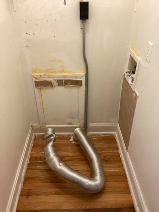 A utility space with unfinished walls. The access panel is dated and worn. 