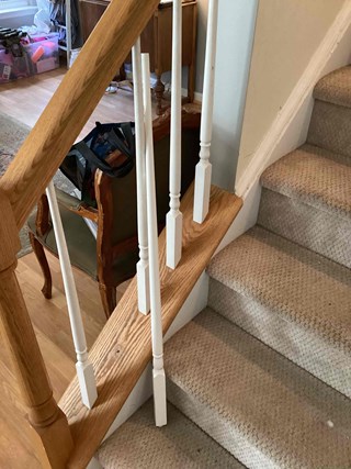 A staircase with broken and detached white balusters. 