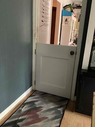 A white half-door installed in a doorway, dividing two rooms.