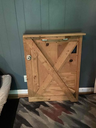 A wooden barn-style door with diagonal and horizontal planks forming a rustic "Z" pattern. 