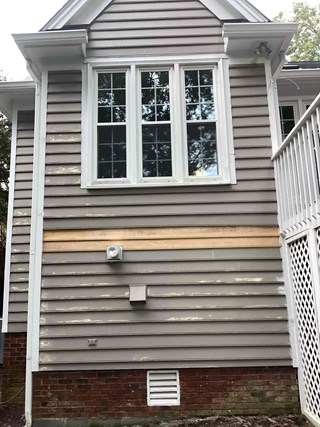 The side of the house with several pieces of siding replaced. 
