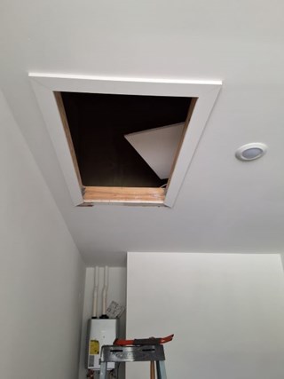 Old attic access with damaged panel and exposed opening in Pearland