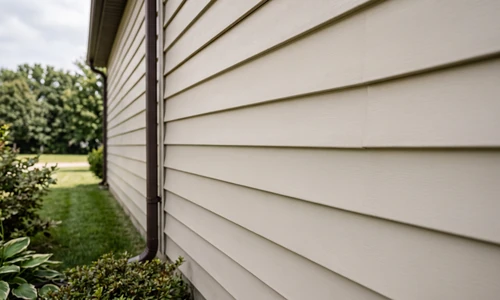 Repaired aluminum siding wall with the replacement panel blended into the original run, even color and clean lock seams, mid-afternoon side light
