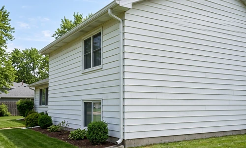 Images/Corporate Site/Blog Images/how-to-fix-gutter-pulling-away-from-house_AHS_generic_081826_img2.webp Repaired level aluminum gutter on a two-storey house with a full-height downspout strapped to the wall