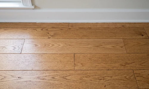 Repaired oak hardwood floor with the replaced board blended into the surrounding grain and sheen