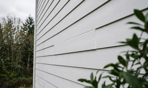 Finished fiber cement siding repair with the replacement plank caulked and primed to match the existing course lines