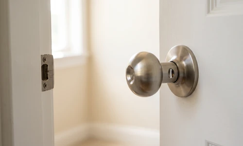 Satin nickel round interior door knob at a three-quarter angle, the small release slot visible in the neck behind the ball