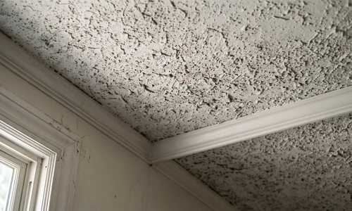 Close-up photograph of an interior gypsum drywall ceiling corner showing heavy popcorn acoustic texture