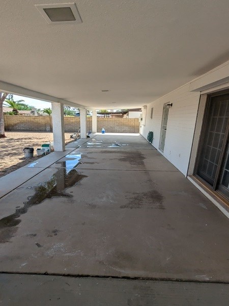 Covered patio with concrete floor, tools, and supplies visible.