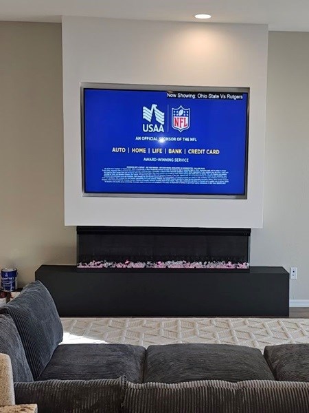 Wall with recessed TV mount above black bench and white rug.