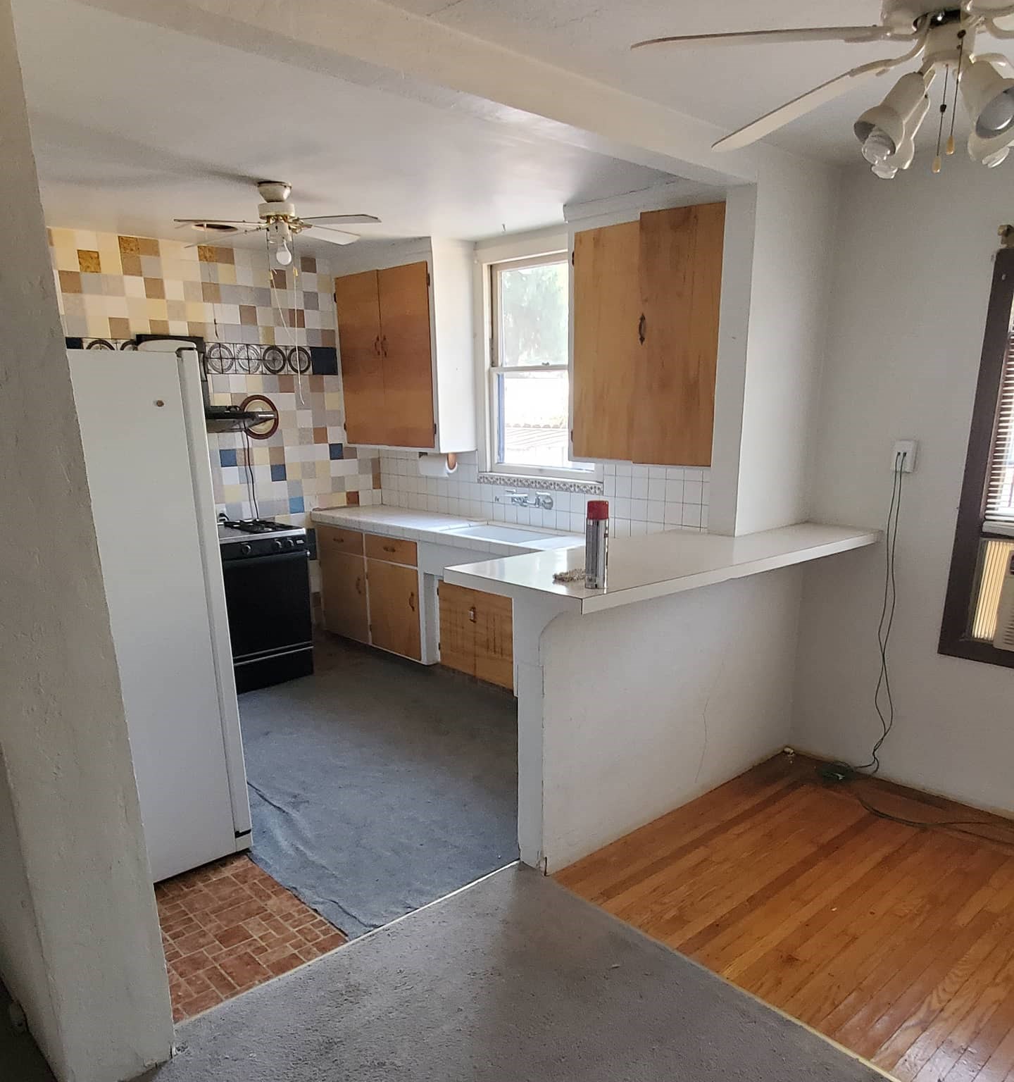 Compact kitchen with wood cabinets, tile backsplash, and ceiling fan.