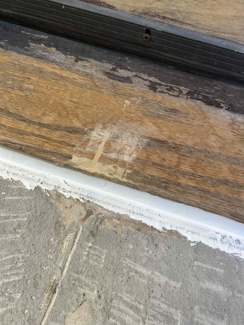 Wood threshold repaired and sealed to the stone step
