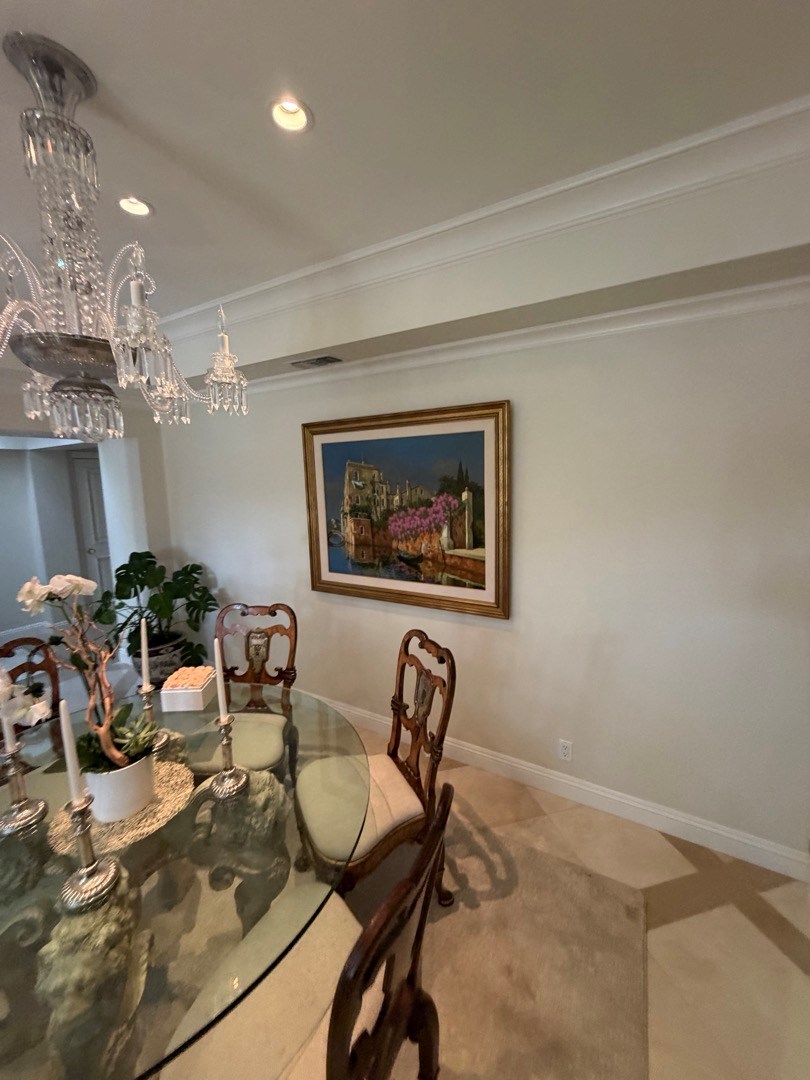Framed painting hung in a Newport Beach dining room near a glass table and chandelier