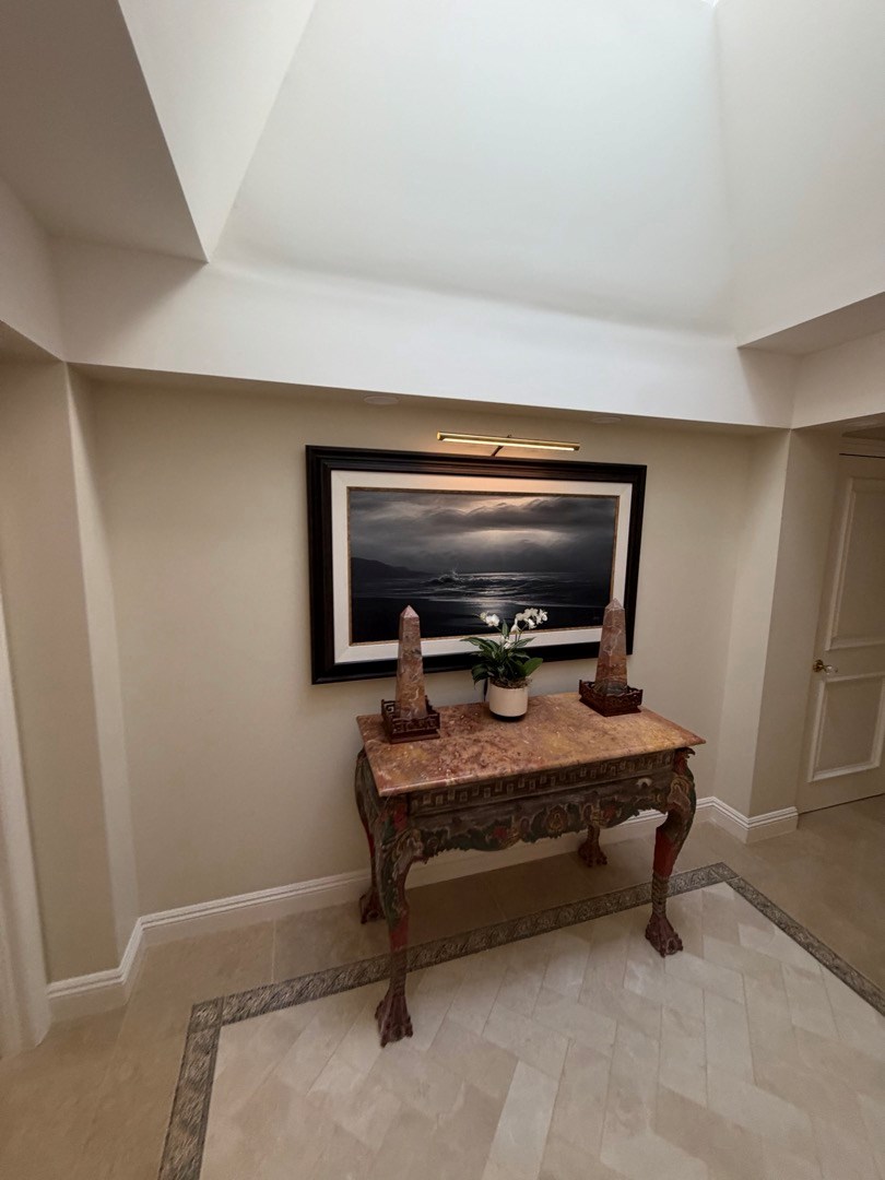 Dark framed artwork hung above a wood entry console in a Newport Beach home