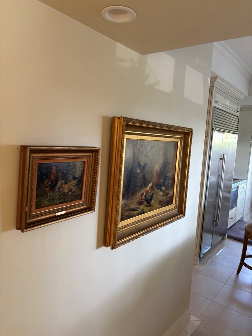 Two framed landscape paintings in gold frames hung in a hallway, Newport Beach art hanging