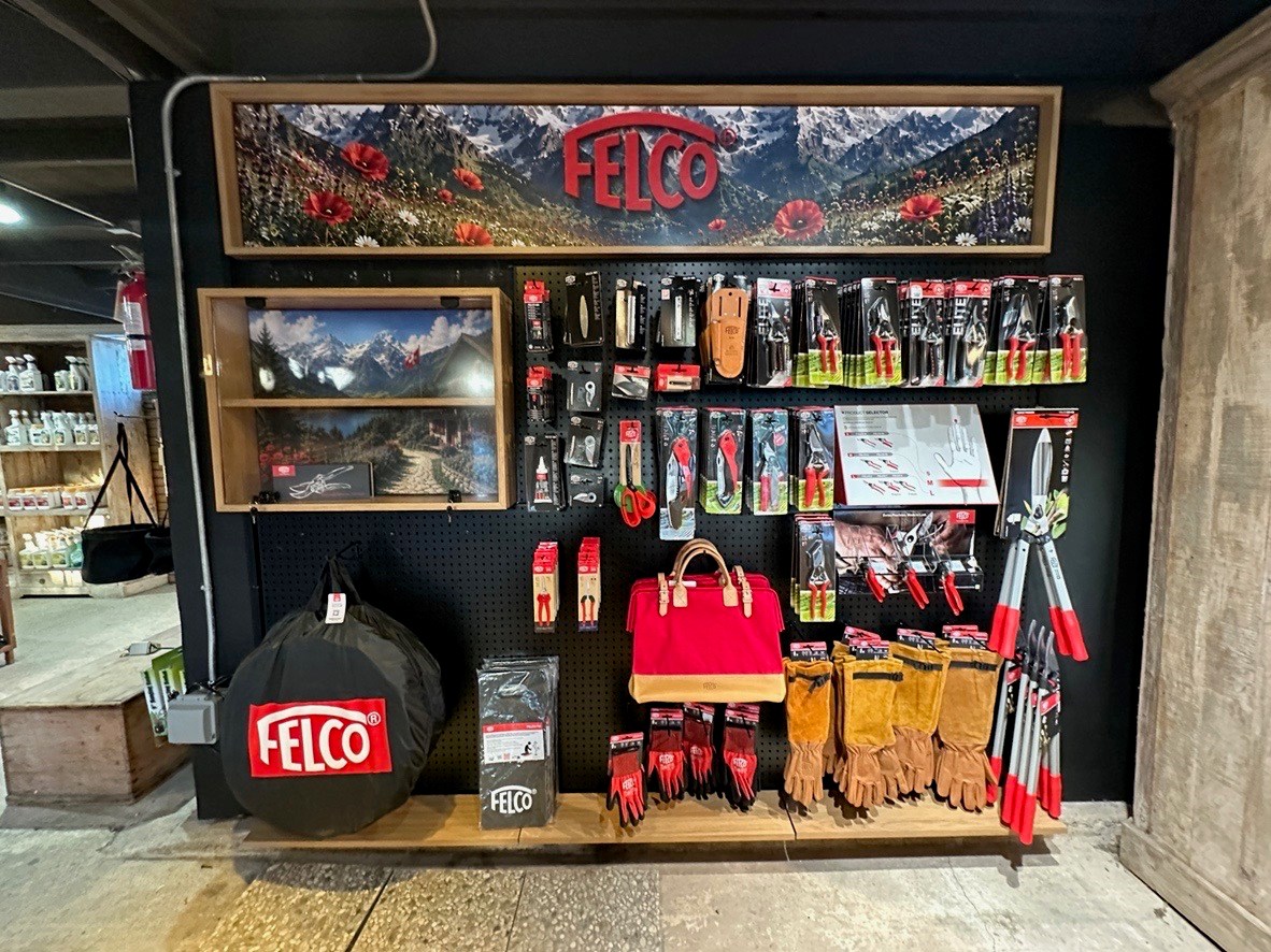 Finished retail display wall, Corona del Mar Finished retail display wall with black pegboard, branded header, shadow box, and garden tools in a Corona del Mar store