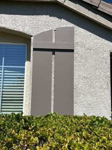 Shutters Rebuild in Folsom Before Weathered wooden shutter next to a window with blinds.