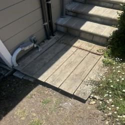 Wooden ramp next to steps and wall, beside a downspout.