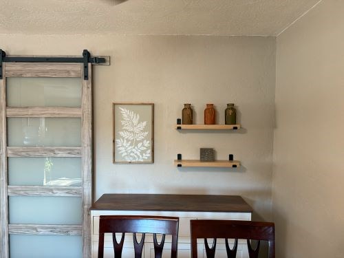 Dining area with sliding door, shelves, and framed art.