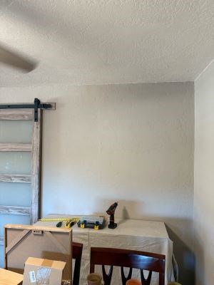 Room with tools on covered table, barn door on left.