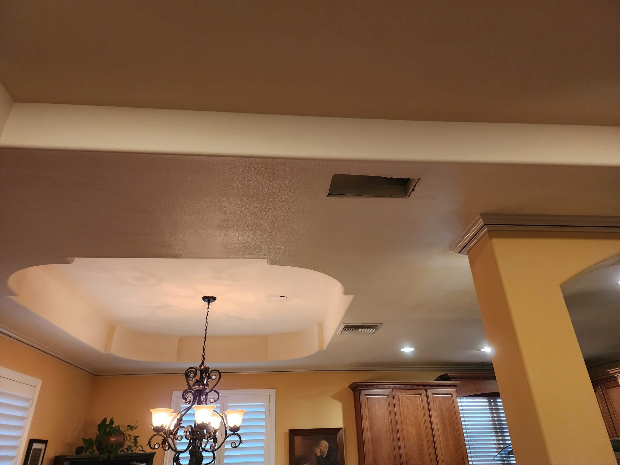 Room ceiling with light fixture and a hole.