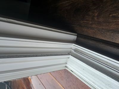 Close-up of a white window frame with wood flooring.