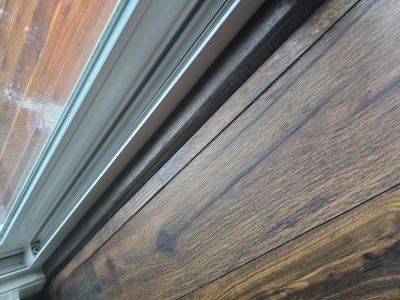 Close-up of wooden floor by a window before handyman project.