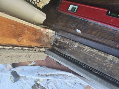 Door frame damage with tools and level; pre-repair image.