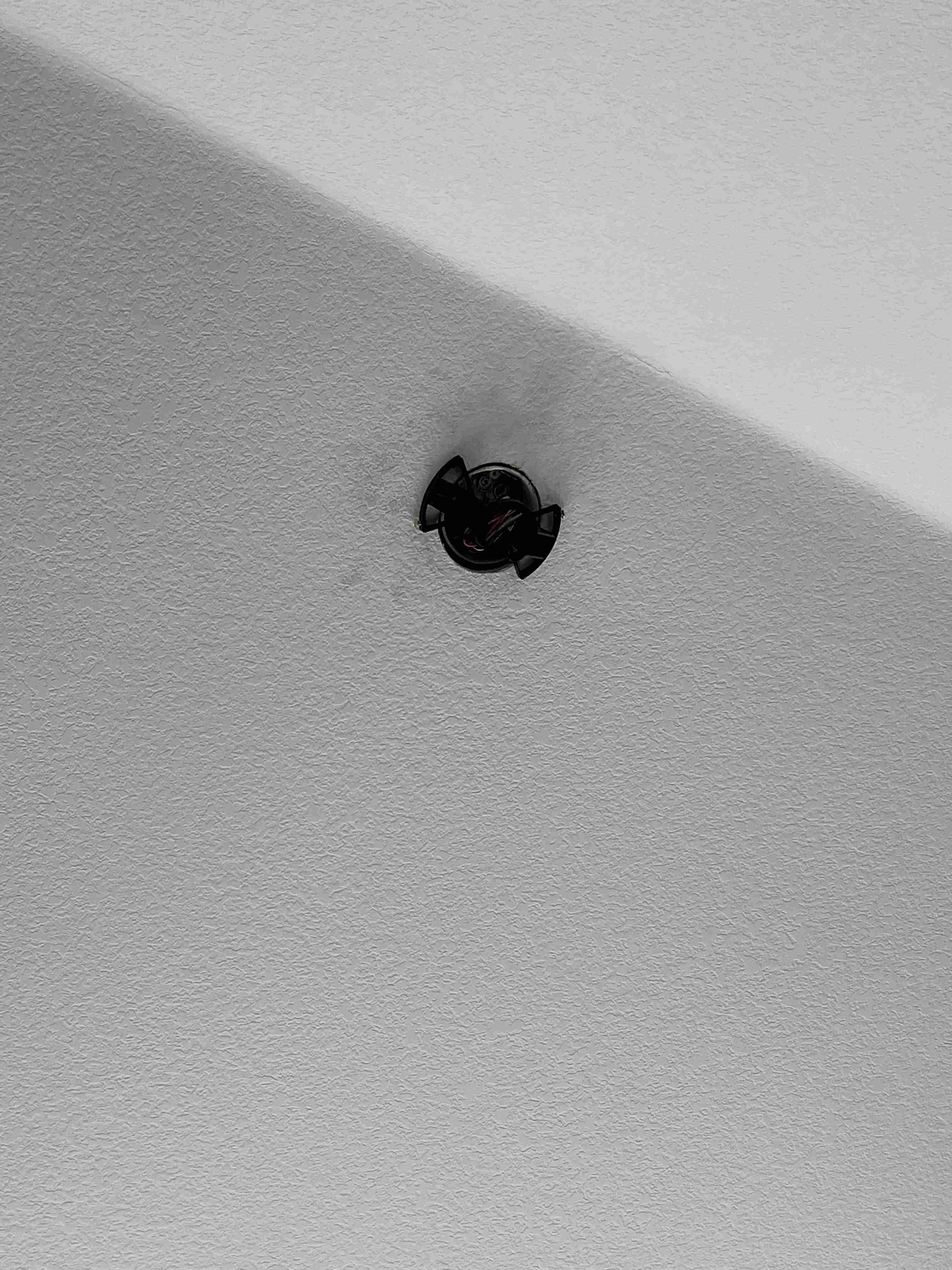B&W image of a ceiling fan mounting bracket on a sloped ceiling.