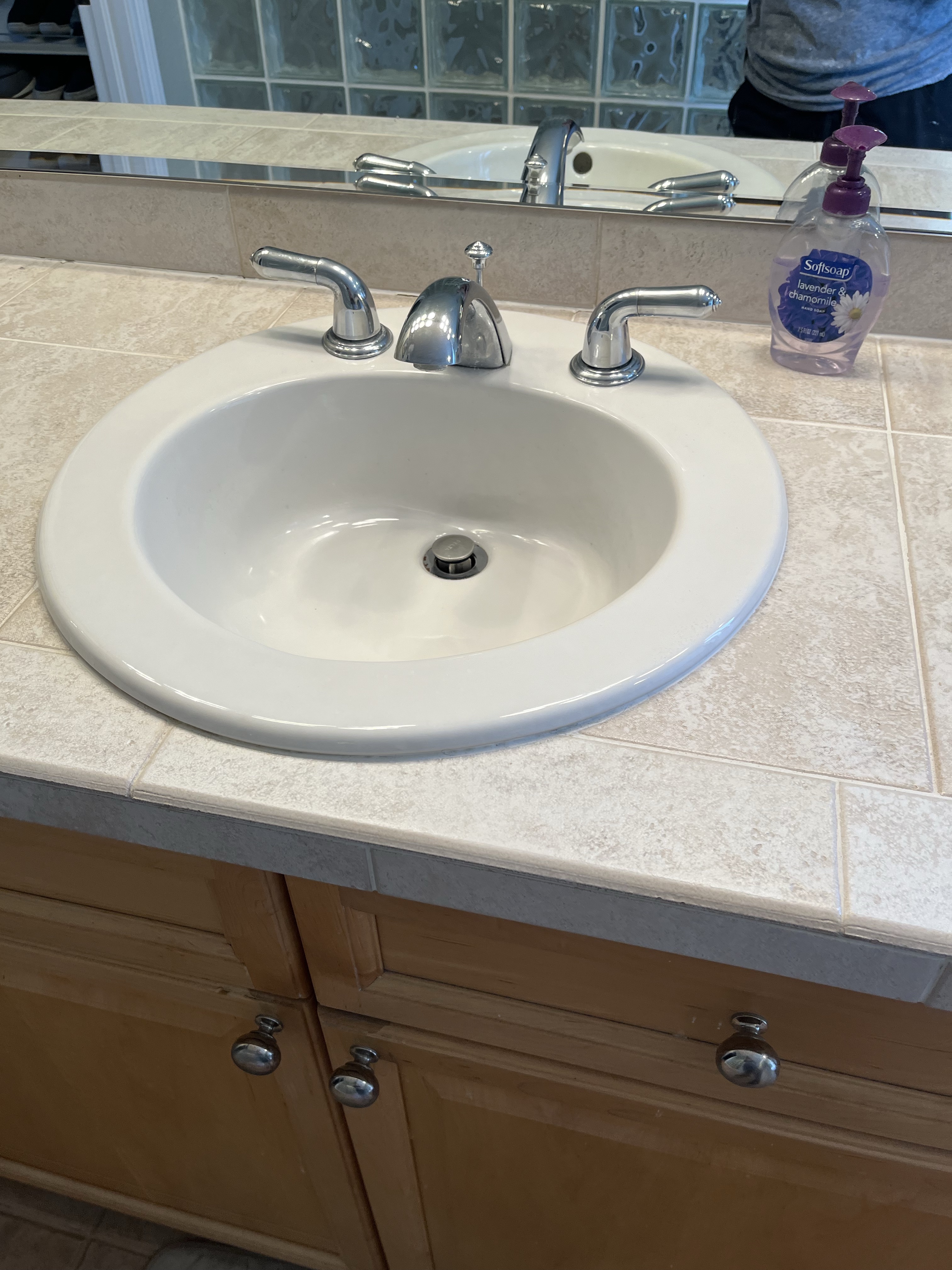 Bathroom sink with faucet and soap in a tiled counter.
