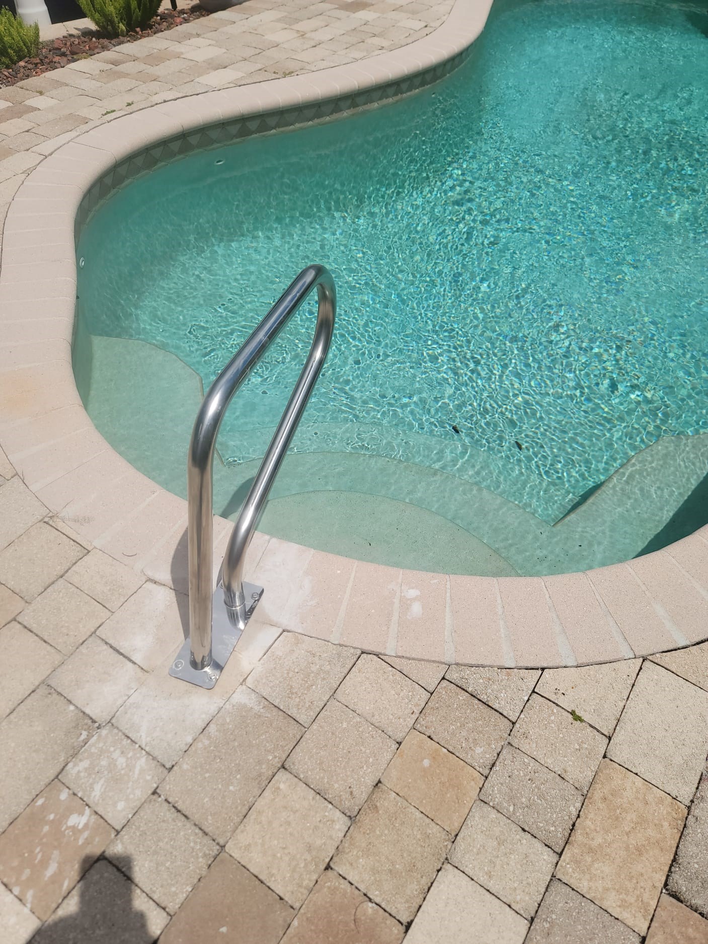 Newly installed pool handrail on tiled deck by the water.