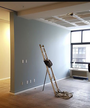 Room with ladder, ceiling work, and partially painted wall.