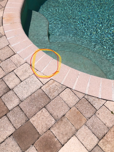 Brick poolside with cracked tile circled in orange.