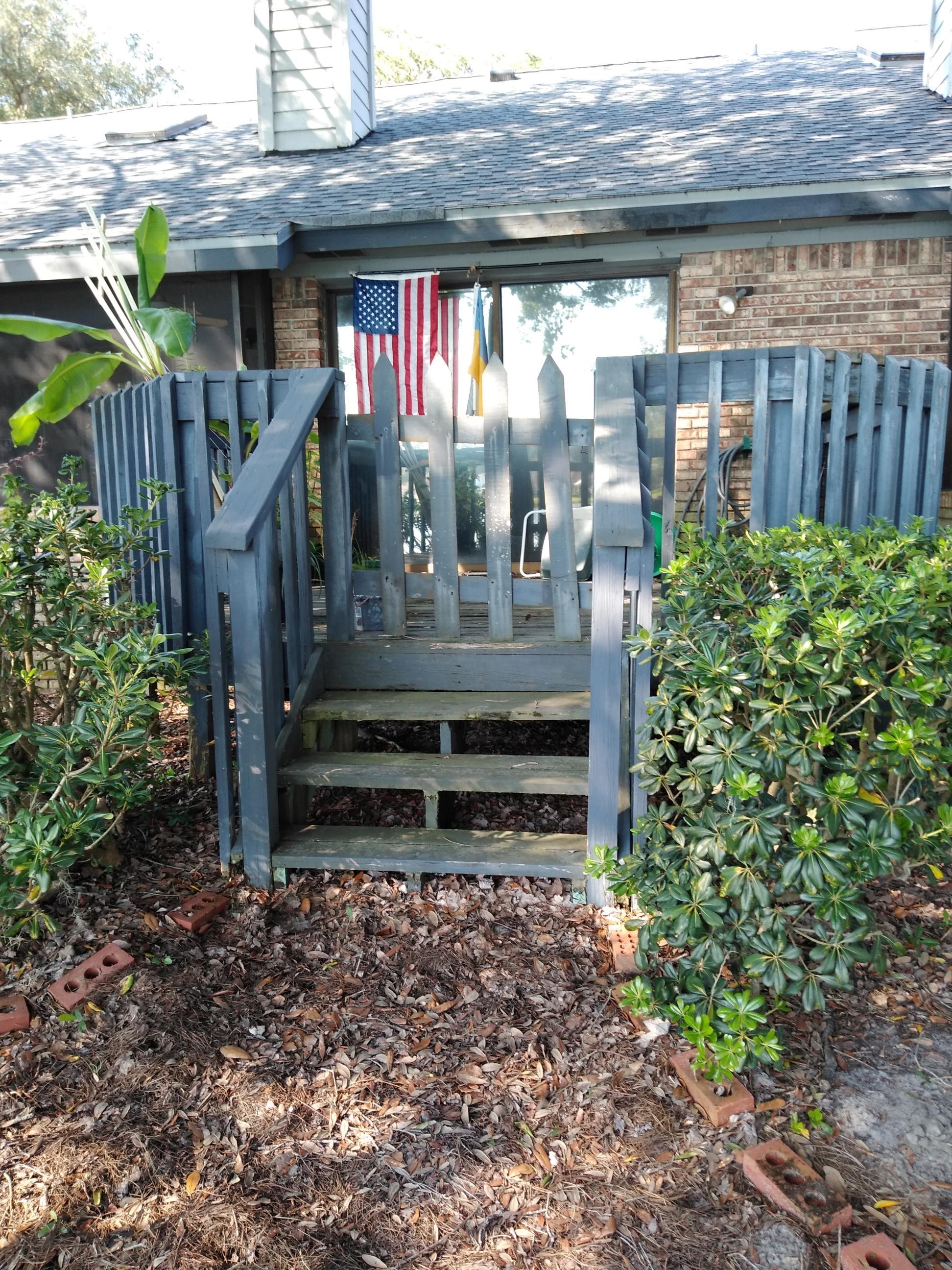 Small wooden porch with steps and two hanging flags.