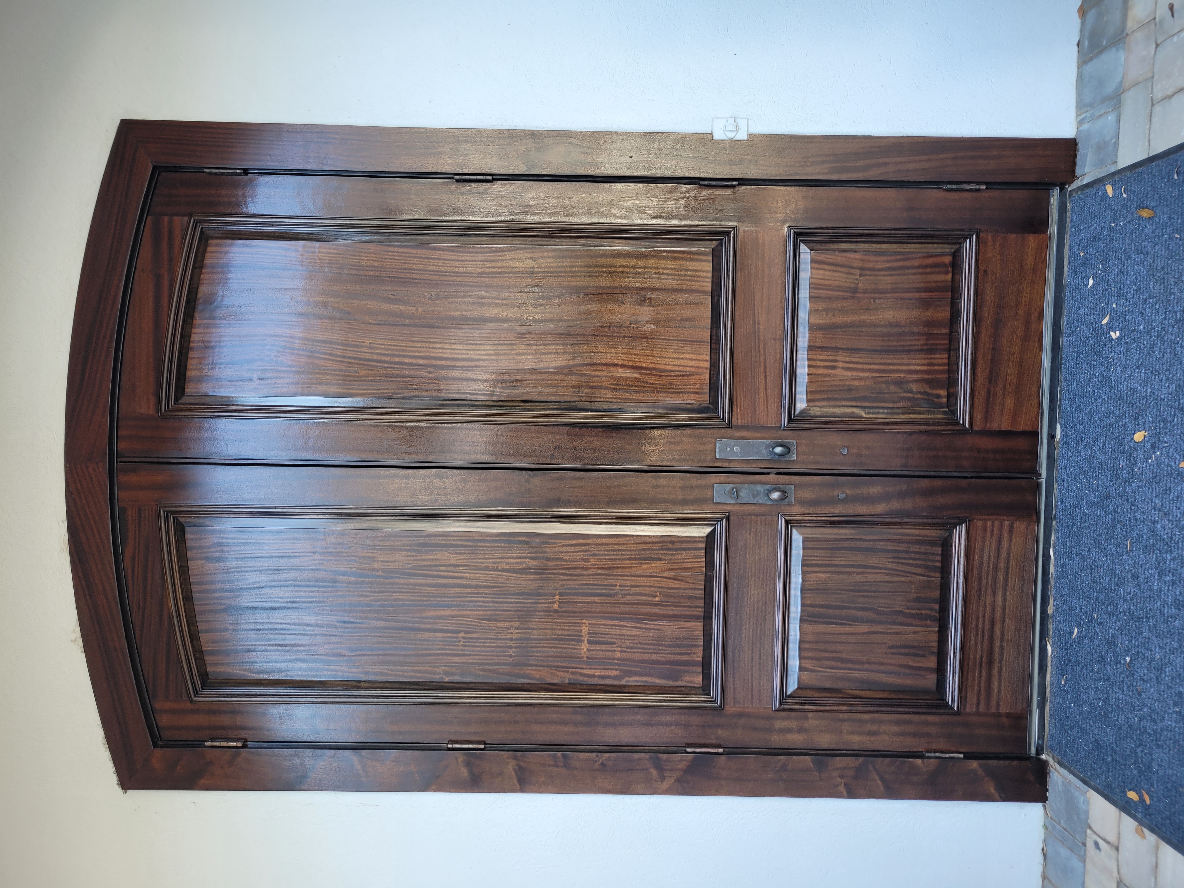 Dark wood double doors with arched frame and handles.