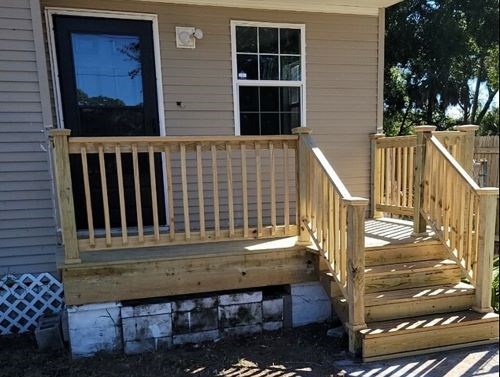 Wooden porch and steps on a house against a blue sky.